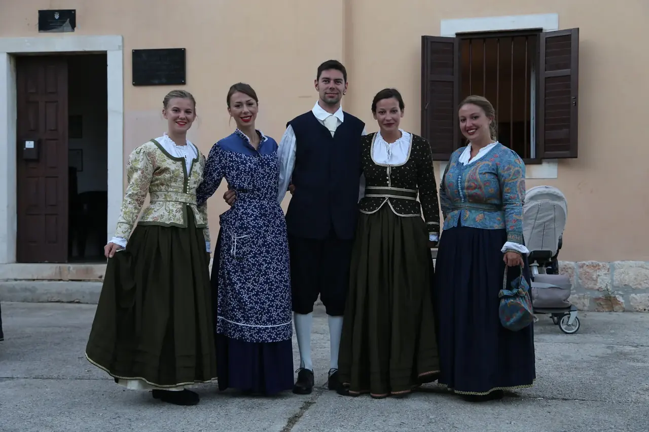 Pet mladih plesača u nošnjama ispred kuće u Silbi.