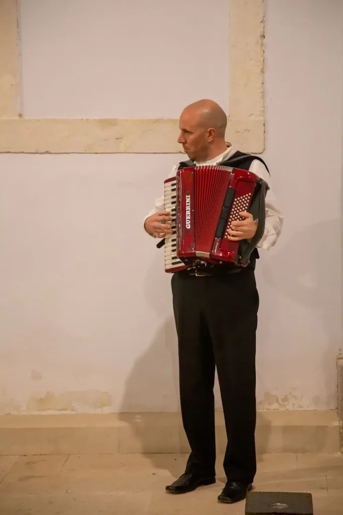 Harmonikaš u nošnji svira u atriju.